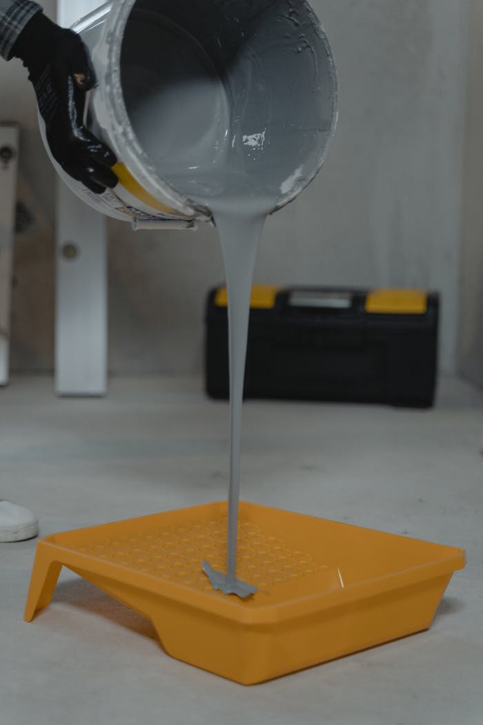 home-hero-bg Gray paint pouring into a yellow tray, ideal for room renovation projects.